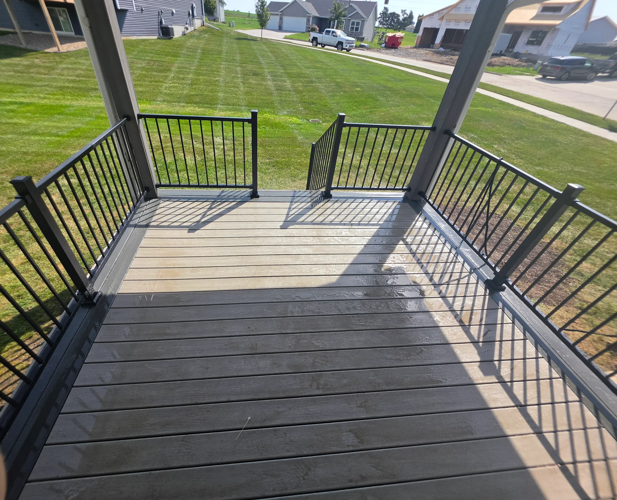 View across a completed composite deck with black metal railings and stairs