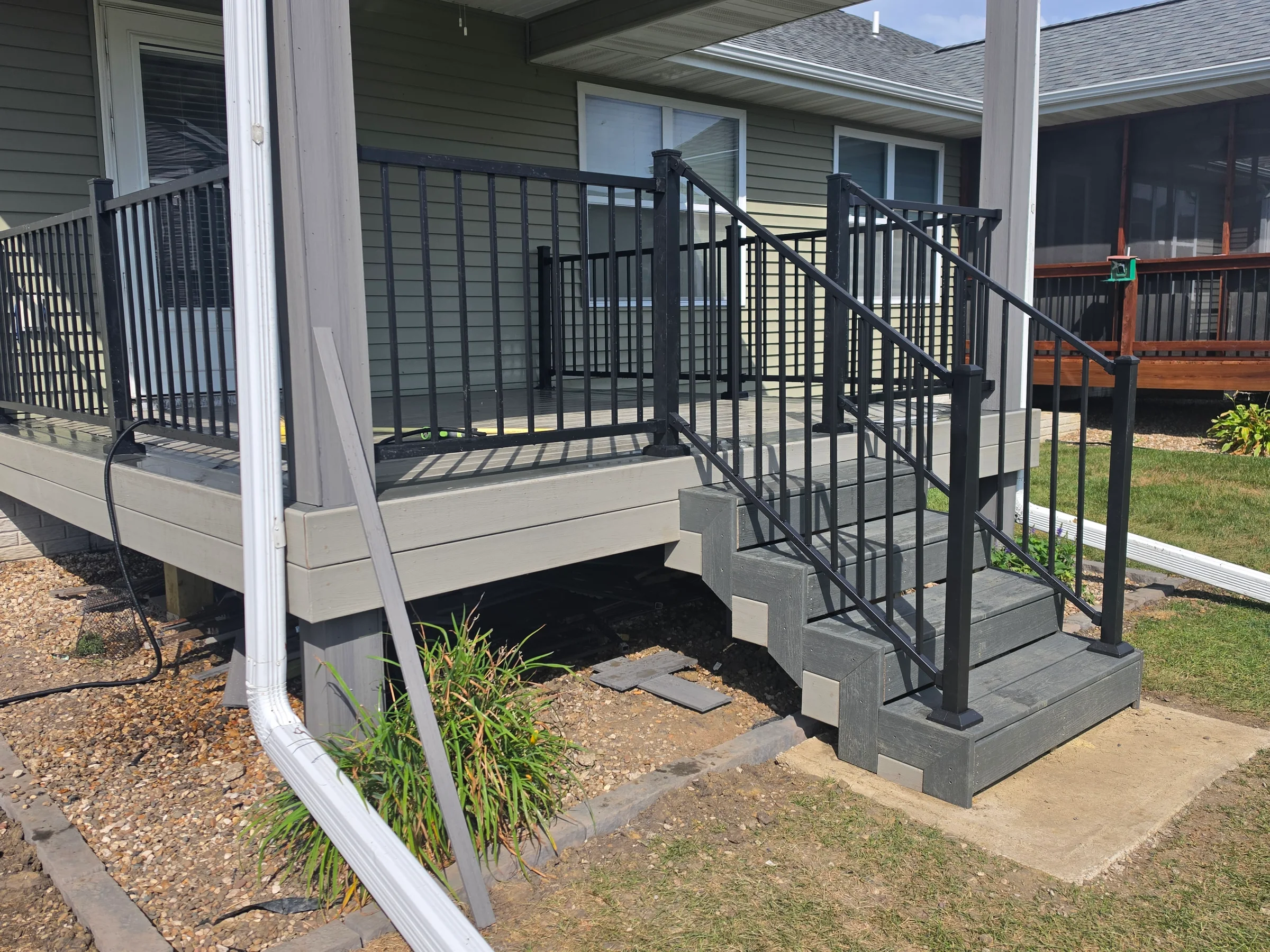 Completed residential deck with stairs and black metal railing