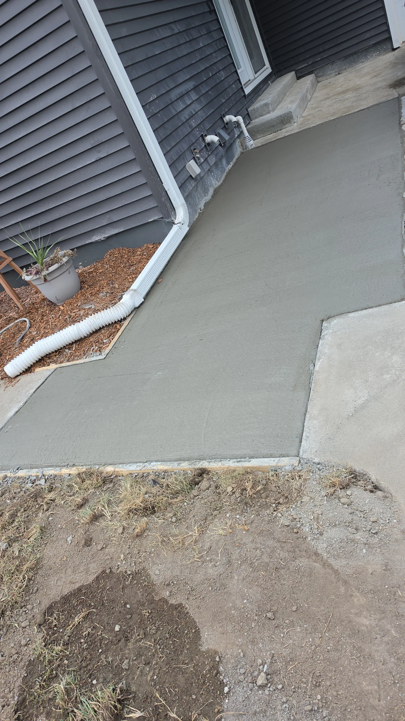Newly finished residential concrete slab beside a house and existing walkway