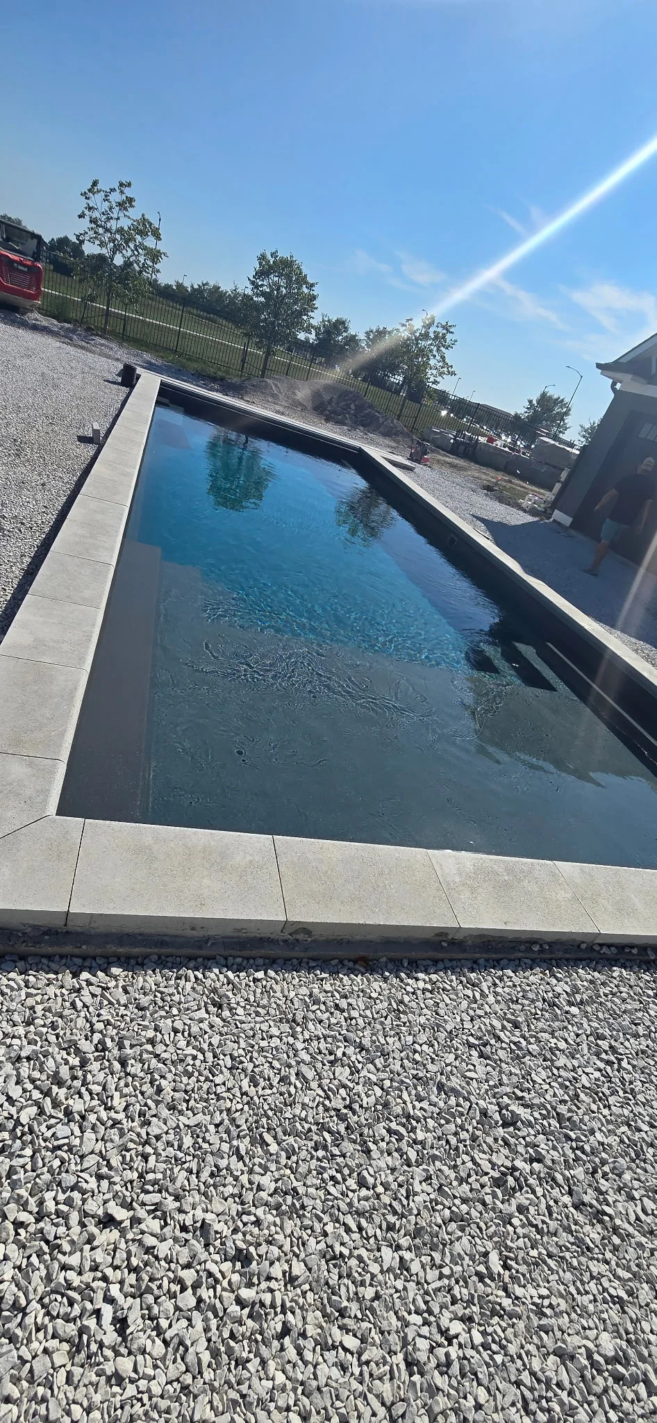 In-ground fiberglass pool surrounded by prepared stone base and concrete coping